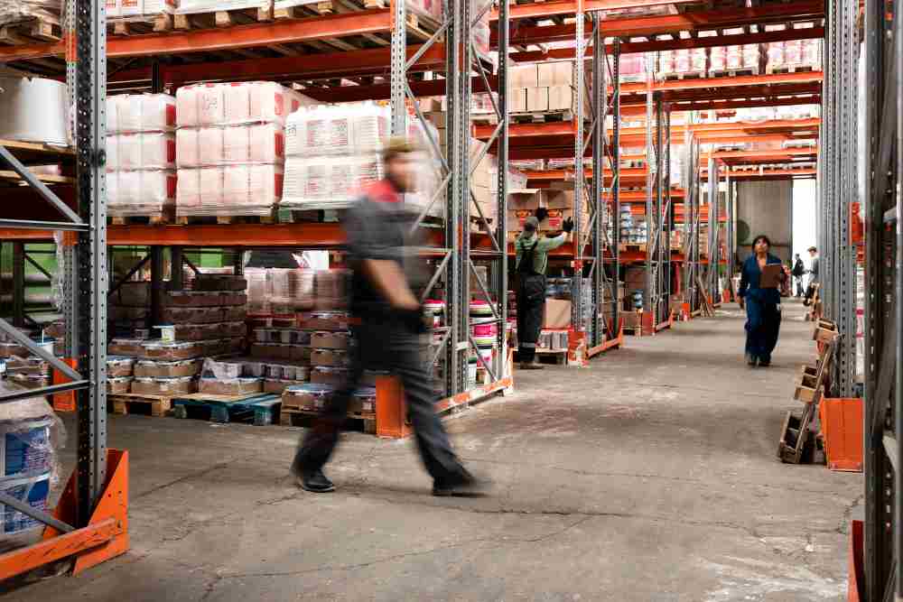 A man walking in a warehouse with heavy duty rack.