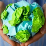 A person holding a paper globe representing waste disposal, zero waste lifestyle for global ecological balance