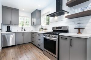 Luxury kitchen interior with steel and wood cabinets, shiny wood floors, faded black glass oven, and bright ceiling with scenic view.
